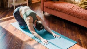 Middle aged woman practices extended child's pose to reduce stress. 