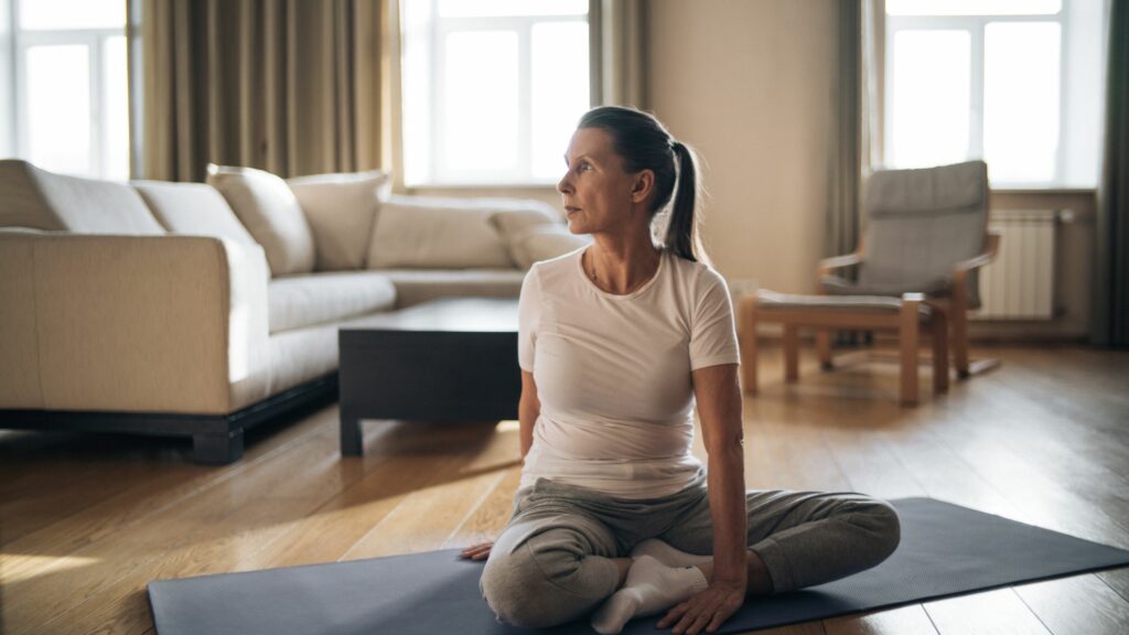 A woman with greying hair in a pony tail uses yoga to help with menopause symptoms