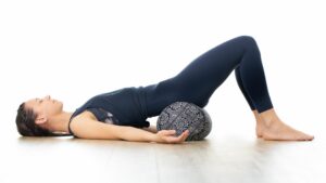 Woman demonstrates supported bridge pose for sleep