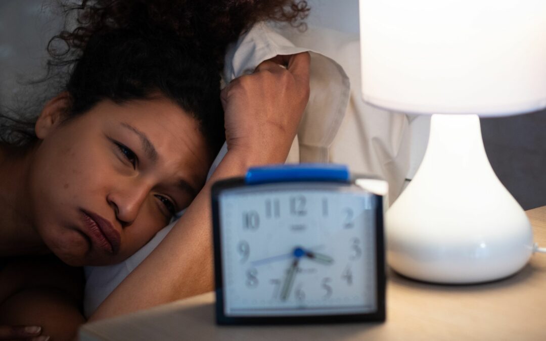 Middle aged woman can't sleep, she lies in bed staring at a clock that reads 3:30 am