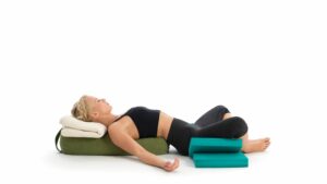 Woman demonstrates restorative yoga for sleep, reclined supta baddha konasana