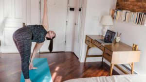 Middle aged woman does standing yoga in her bedroom to improve her sleep