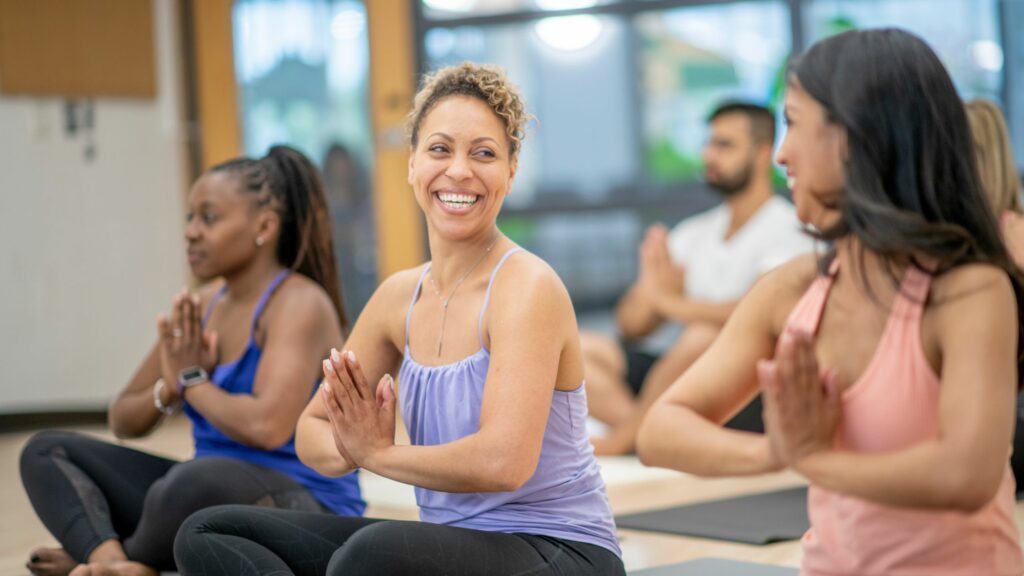 Smiling middle aged woman does yoga with her friends to reduce stress. 
